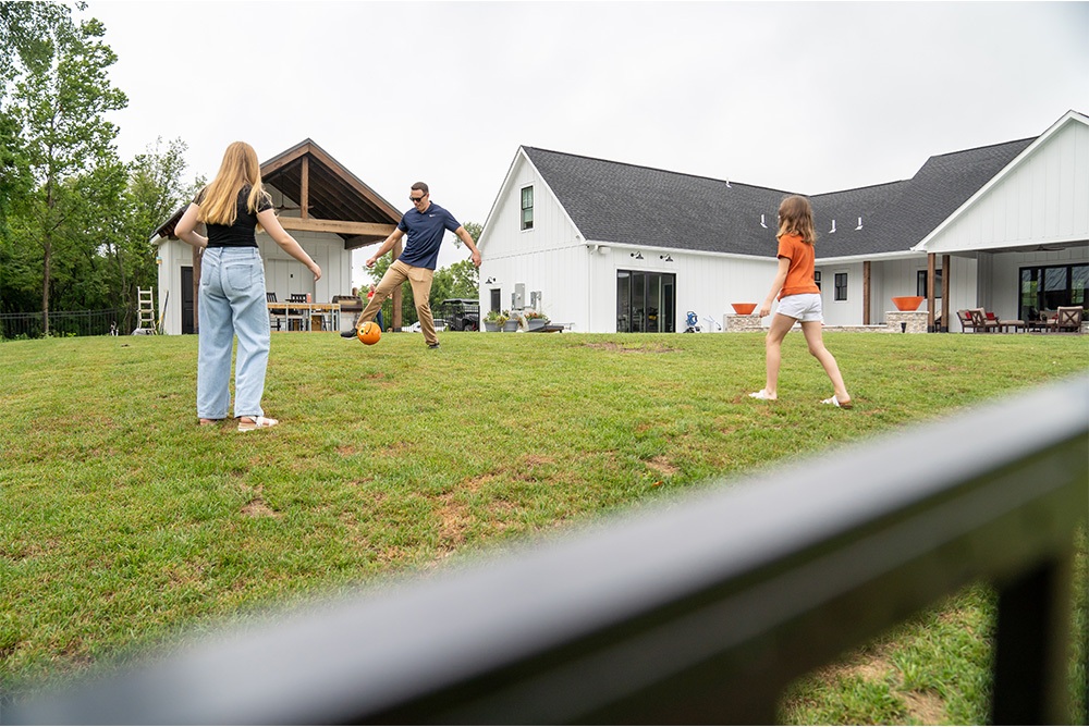 250626-FDD-JuneBlog-Img6-Family Family playing with ball in large, fenced-in yard