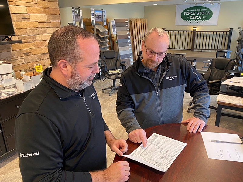Fence & Deck salesman talking to customer and explaining plans