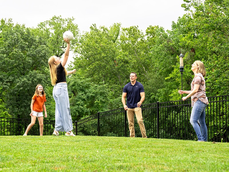 About Us Feature 3 Family playing volleyball in fenced in yard