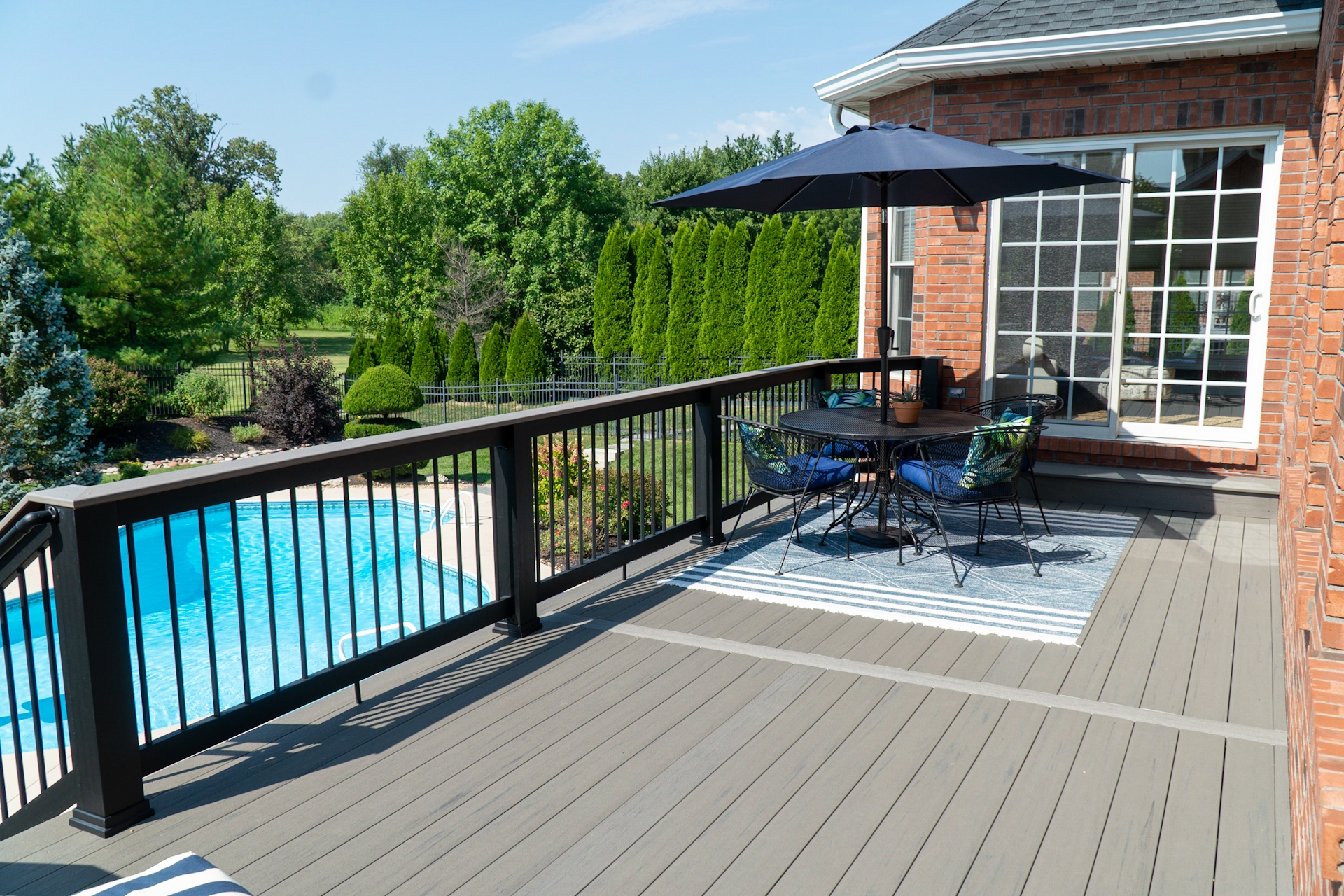 A high deck with a railing overlooks a pool