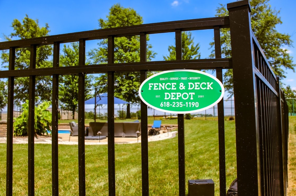 Fence and Deck Depot sign on a metal fence in Wildwood, MO
