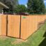 Corner of wood privacy fence with a gate to the backyard