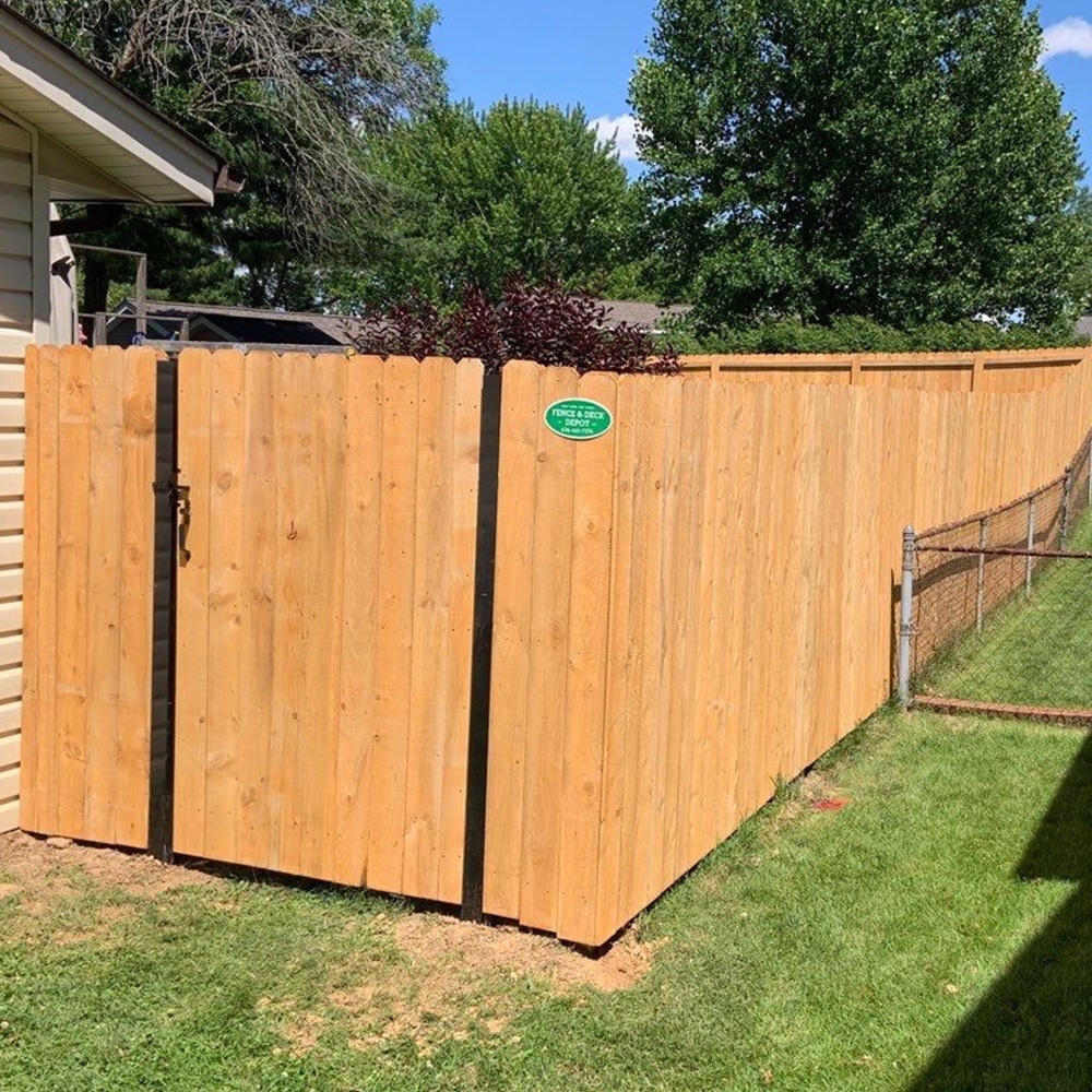 Corner of wood privacy fence with a gate to the backyard