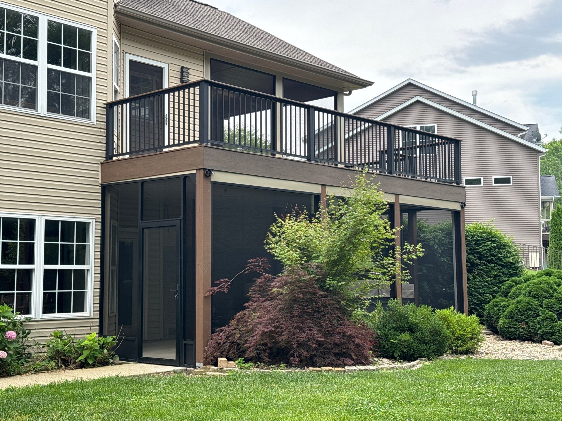Modern brown composite deck with black railings and a screened-in underdeck area below.