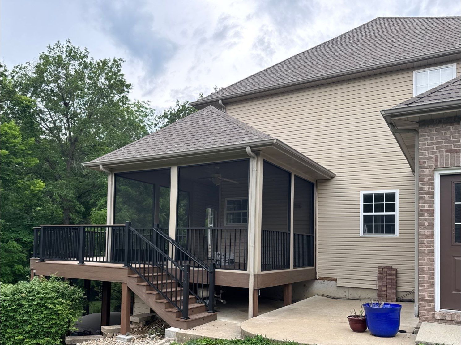 Side view of a new brown composite deck with stairs leading to a screened-in porch.