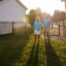 A couple walks in to their fenced-in yard. The fence is black aluminum and has a gate for entry.