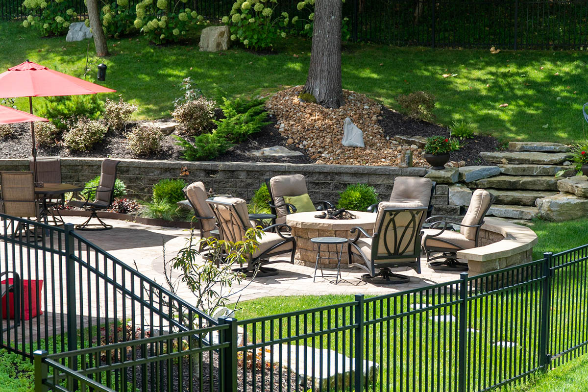 An aluminum fence surrounds a patio area with furniture and gardens.