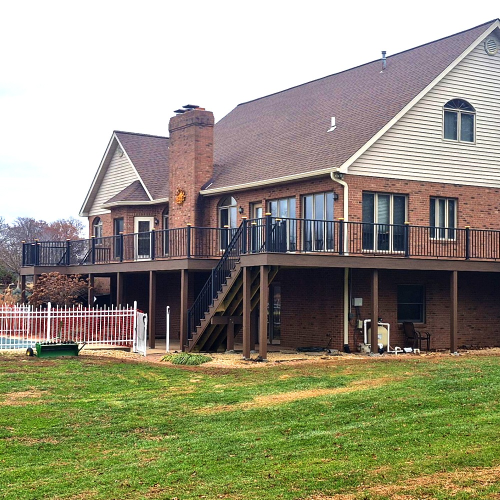 A large deck wraps around a suburban home