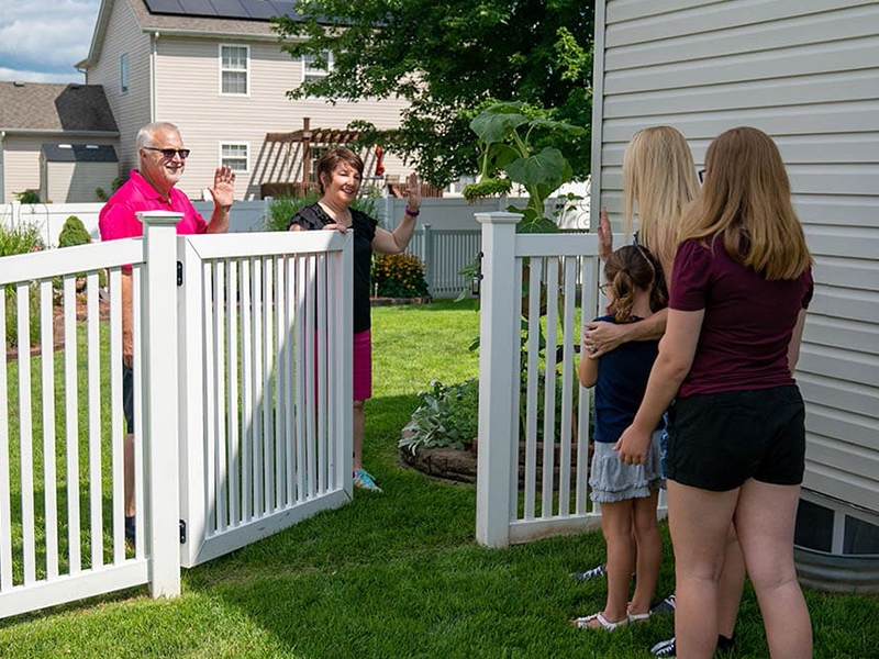 Neighbors greeting each other by fence