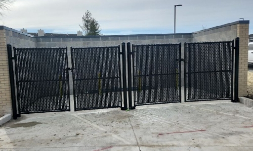 Large commercial dumpster enclosure with chain link gate