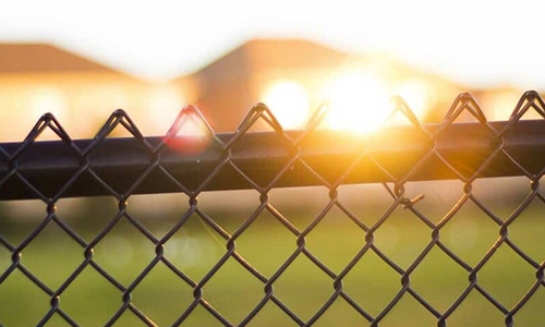 Chain-link fence with sunset in the background