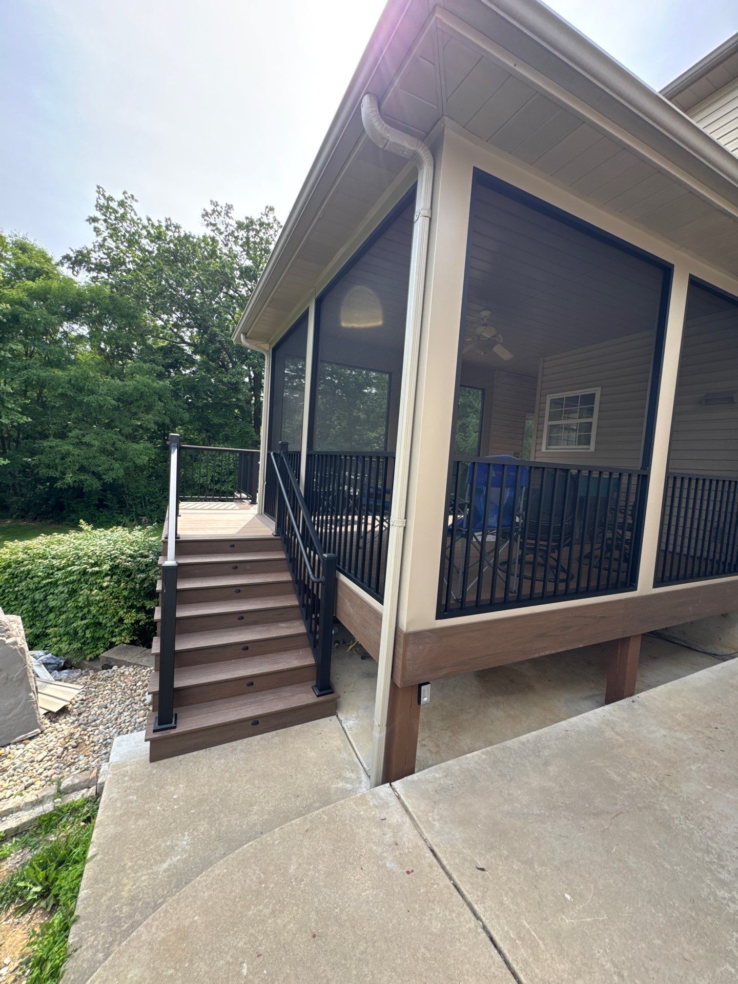 New brown composite deck stairs leading to a screened-in porch.