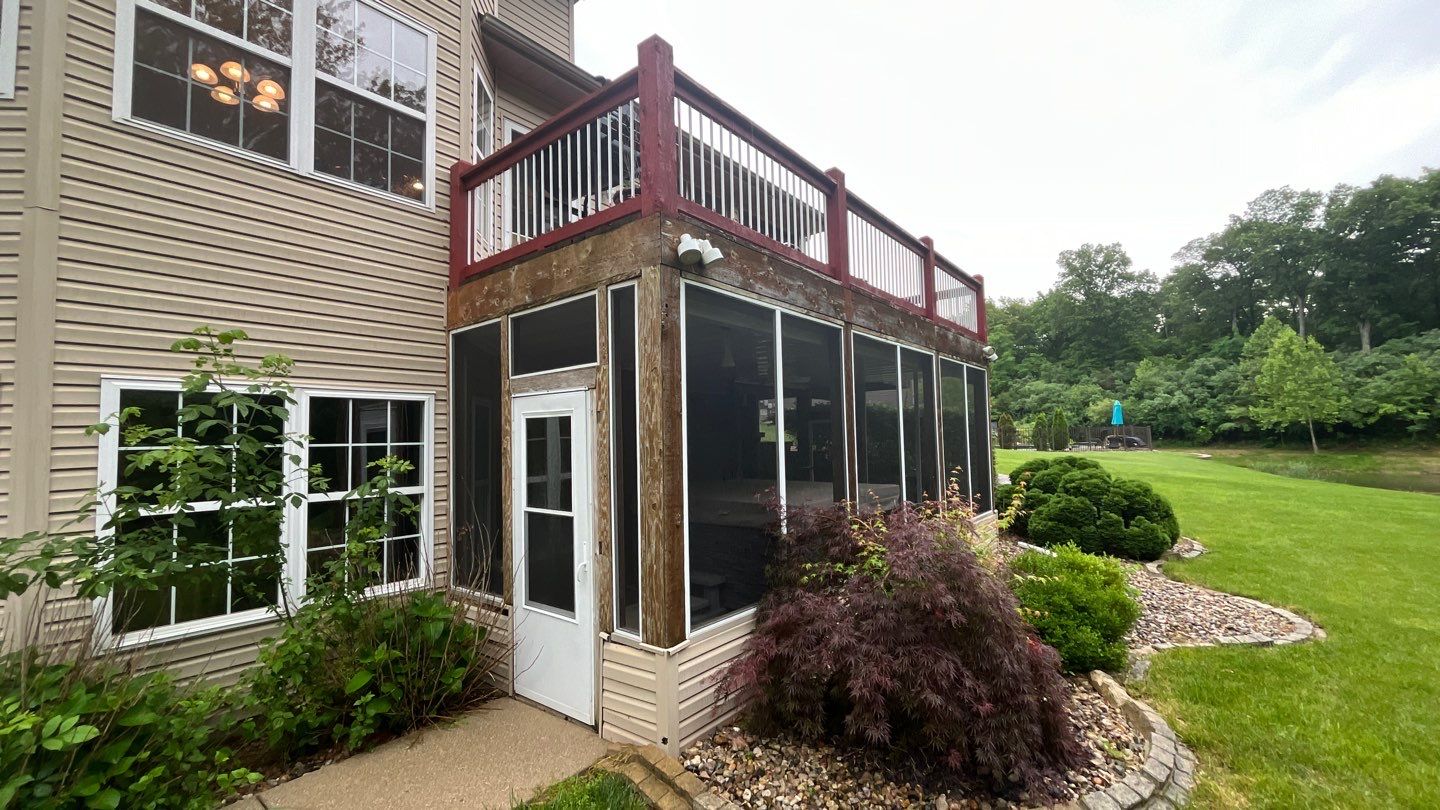 Before image of an old red wood deck and screened-in porch below the deck with a white door.