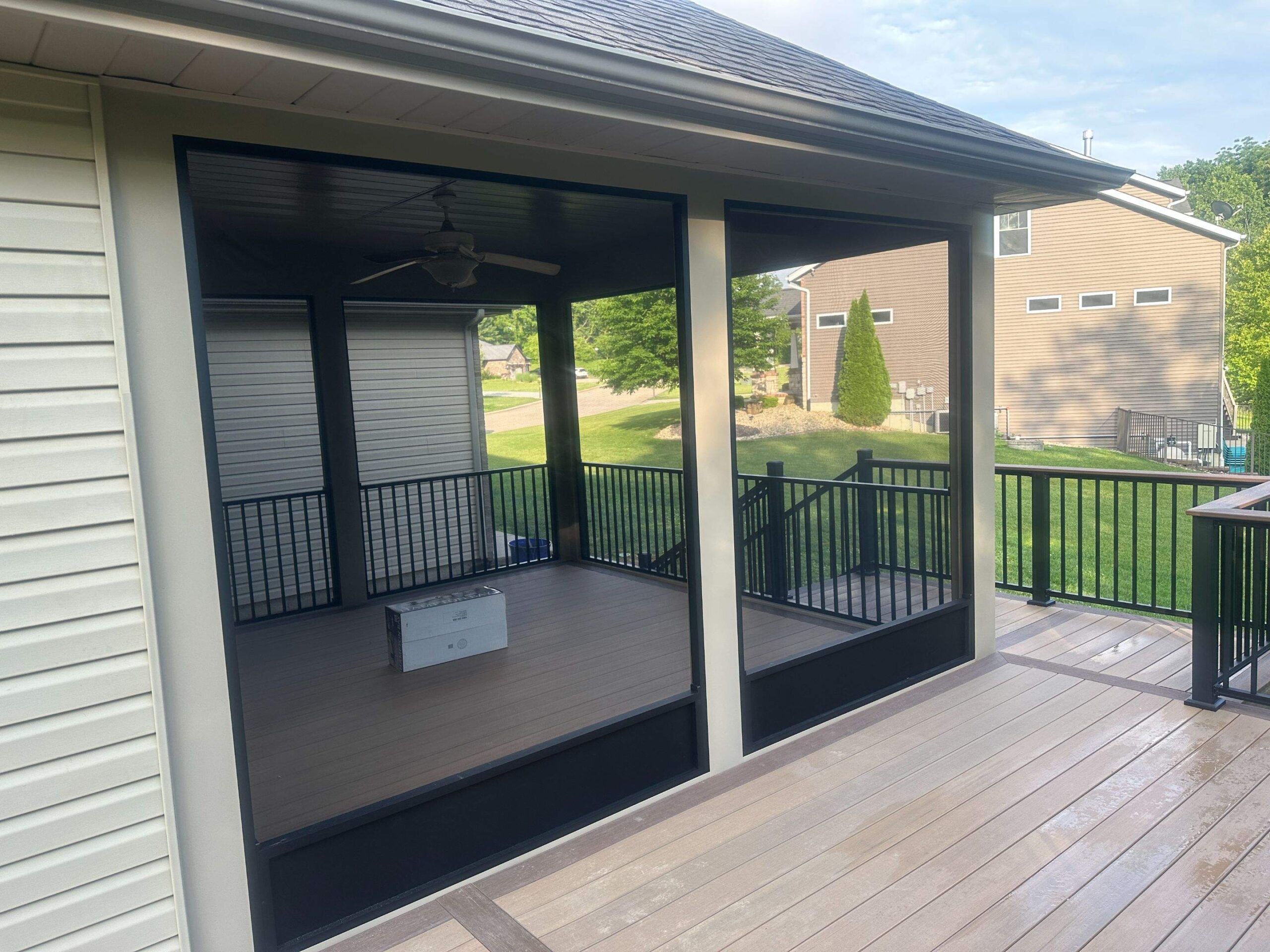 View from a new composite deck with modern metal railings and a view in to a screened-in porch