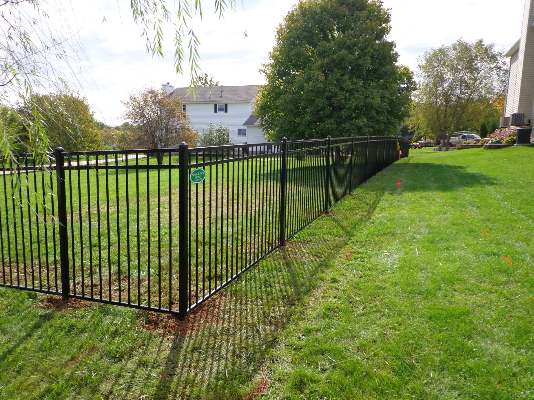 A wide-angle image of a black aluminum fence that surrounds a suburban yard.