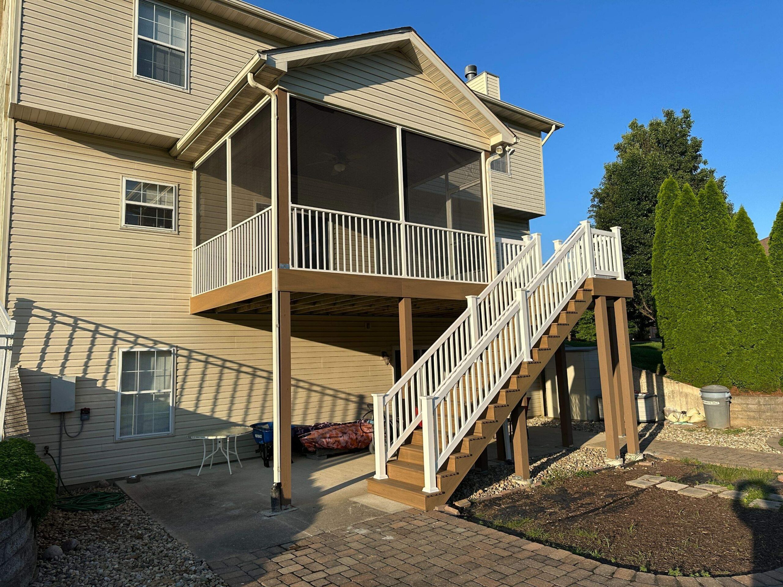A screened in deck with a staircase and white railings