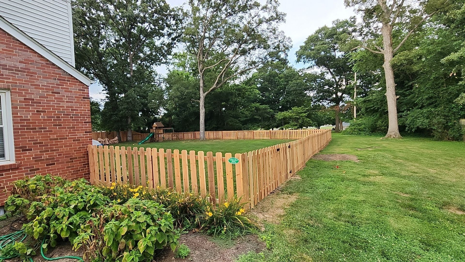 Wooden fence around large backyard with a garden