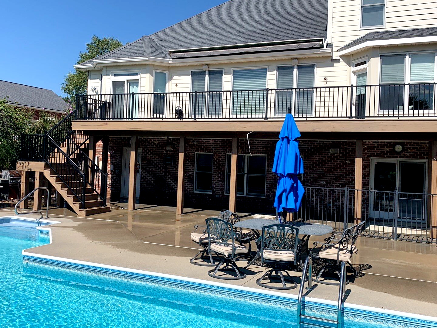 A raised deck overlooks a large blue swimming pool