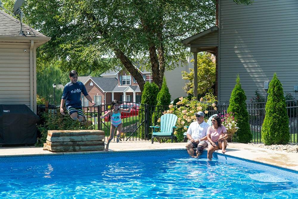 Family using pool that is enclosed with an aluminum fence
