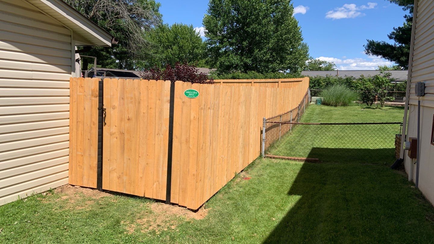 Corner of wood privacy fence with a gate to the backyard