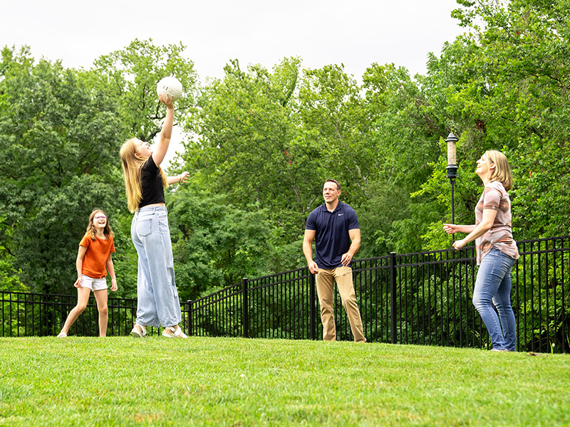 Family playing volleyball in fenced in yard