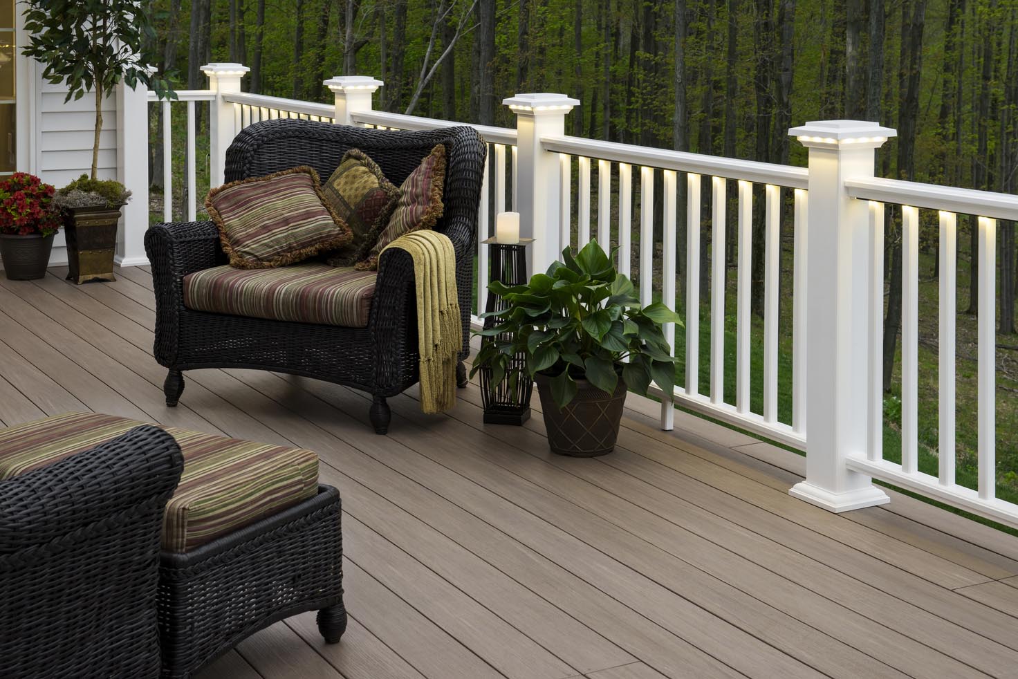 Outdoor deck by Fence & Deck Depot in St. Charles showcasing wicker furniture, illuminated white railing, and potted plants highlighting the elegant outdoor living spaces available with flexible finance options