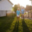A couple walks in to their fenced-in yard. The fence is black aluminum and has a gate for entry.