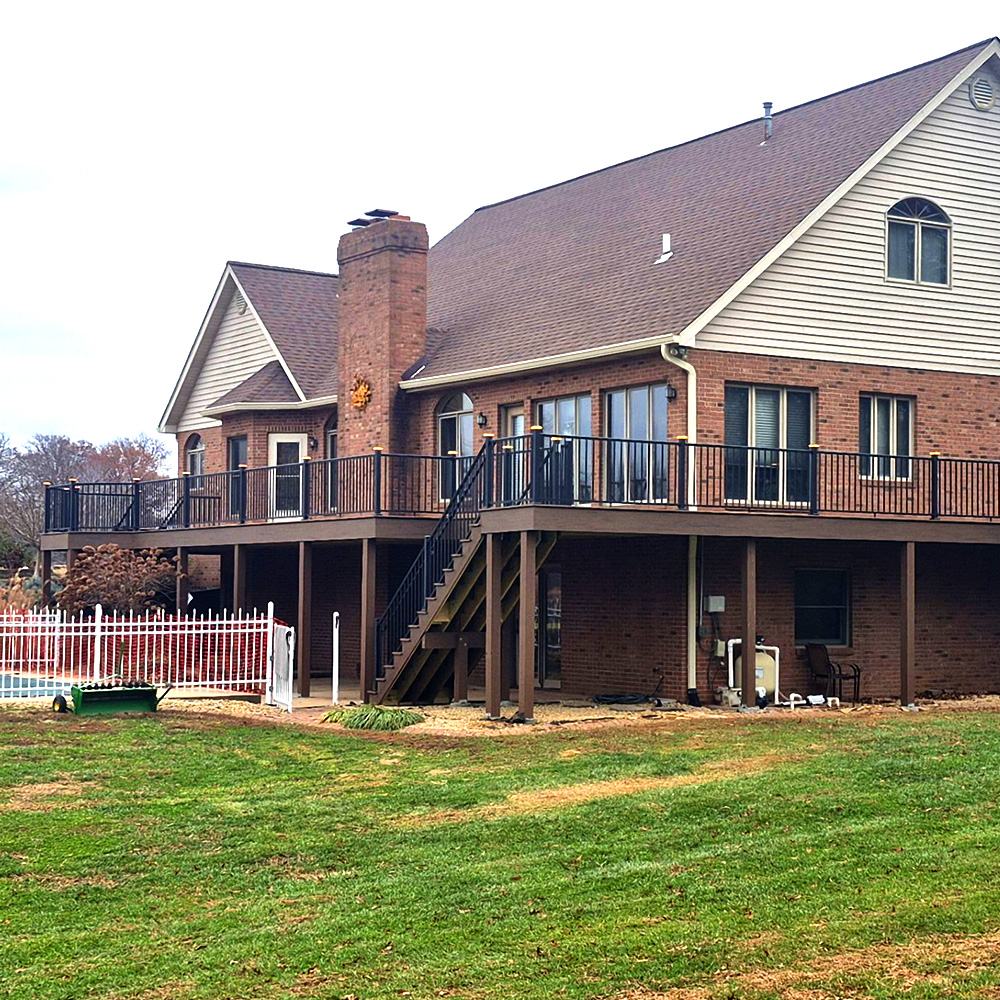 A large deck wraps around a suburban home